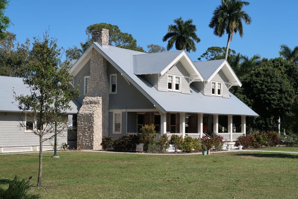 Two-story house with a front lawn and palm trees