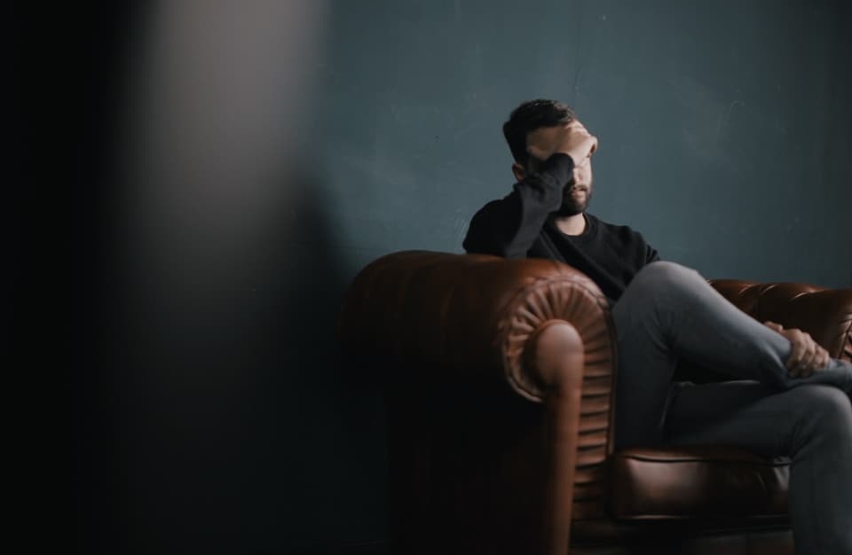 Worried man sitting on a leather chair with his hand on his face